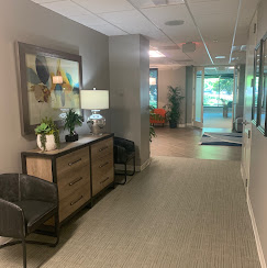 Clean hallway with seating, decor, and office entrances