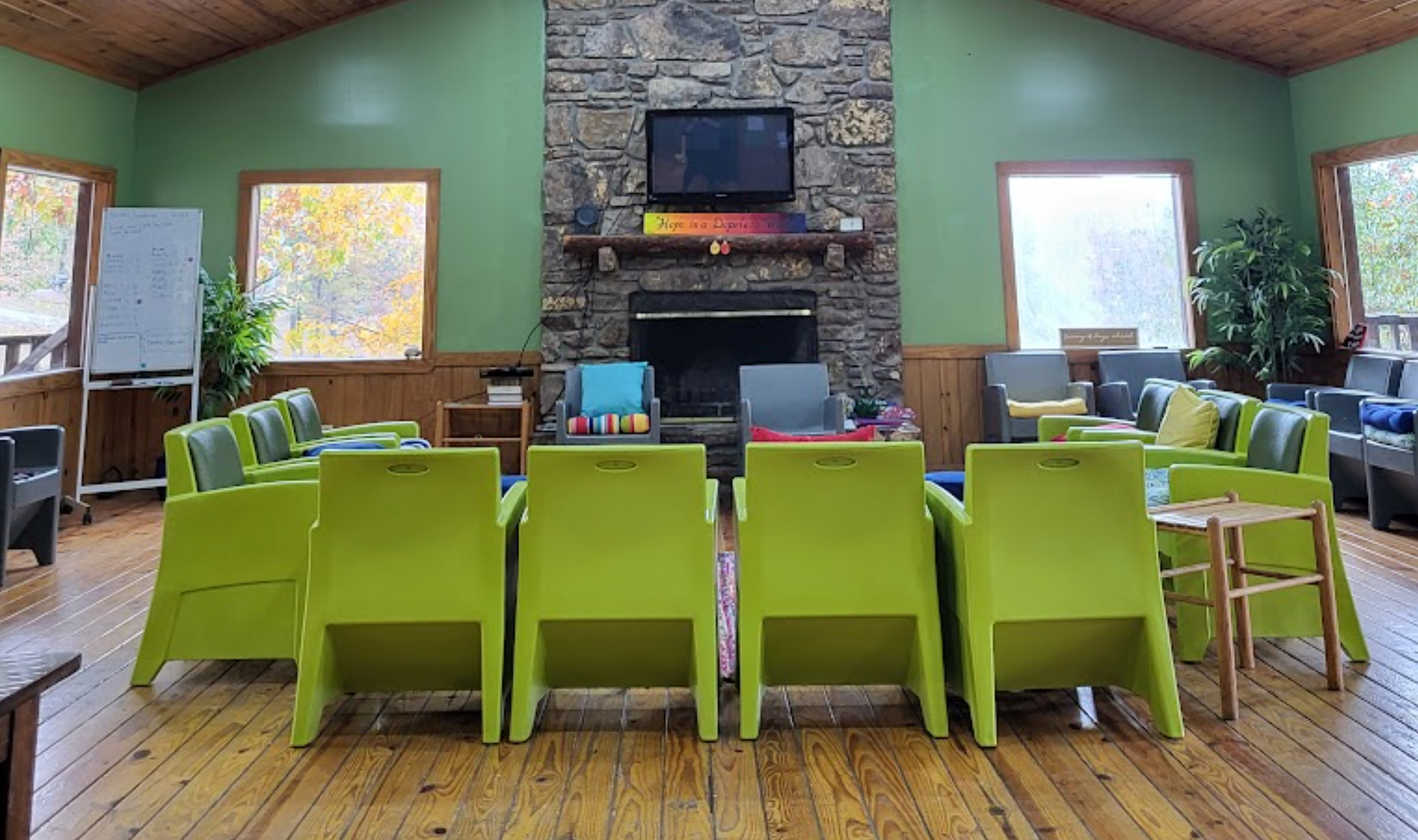 A cozy living room with a stone fireplace and colorful seating.