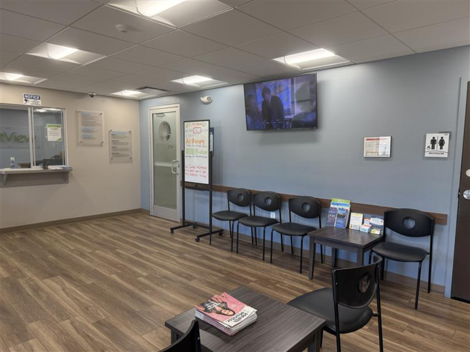 BrightView Health Batavia lobby with black chairs, television, reception window, and wood-look flooring