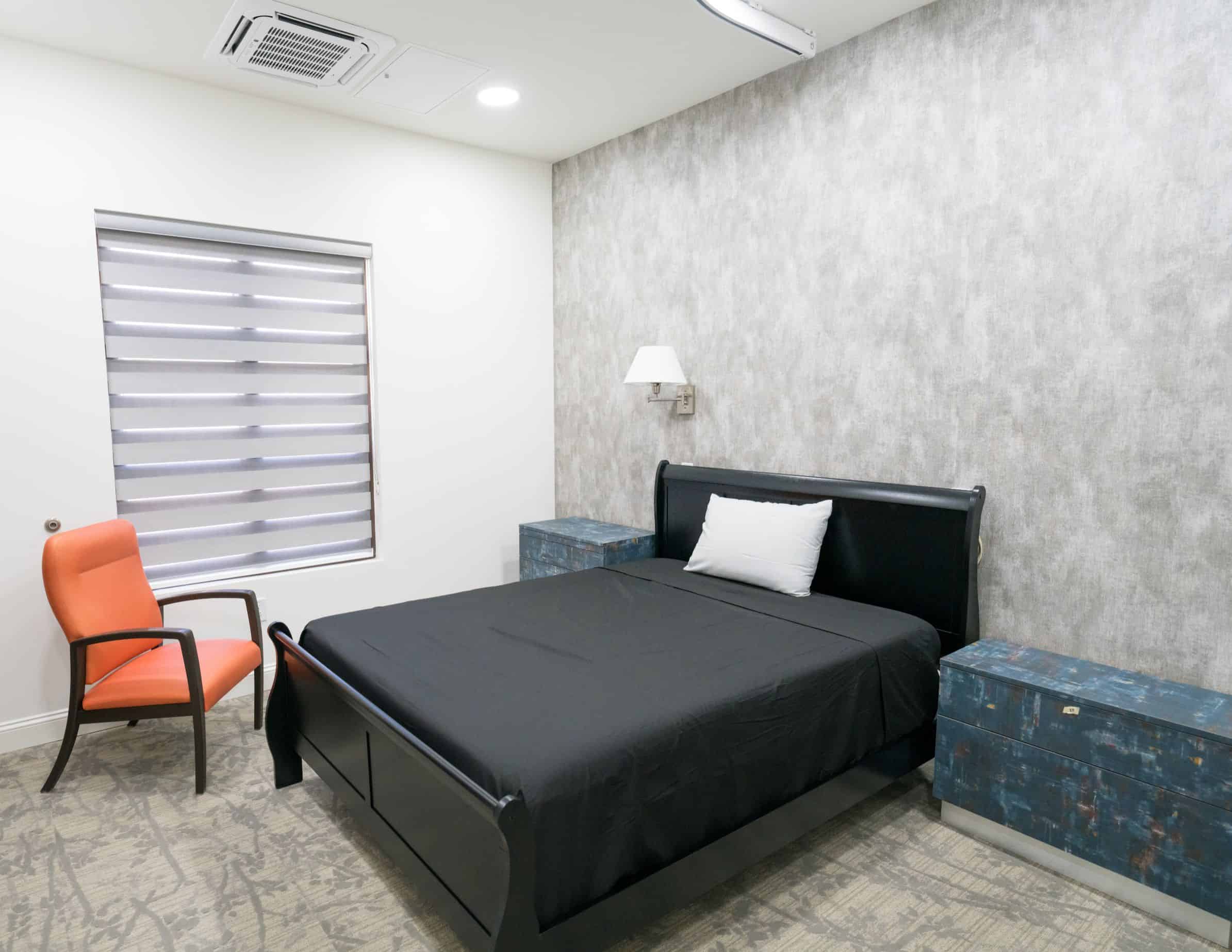 Bedroom with a black bed, gray walls, and a modern design.