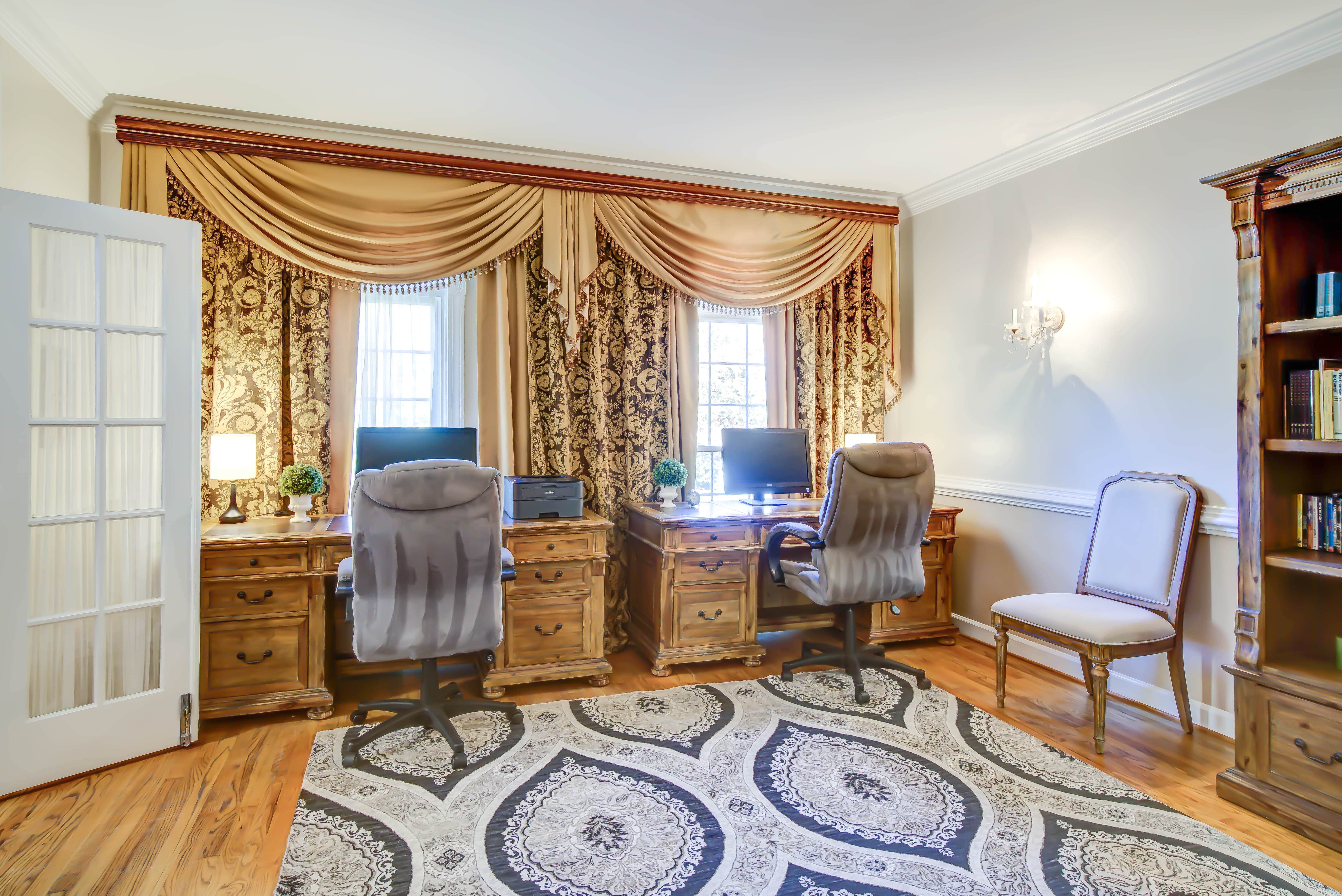 Two desks with office chairs and draped windows