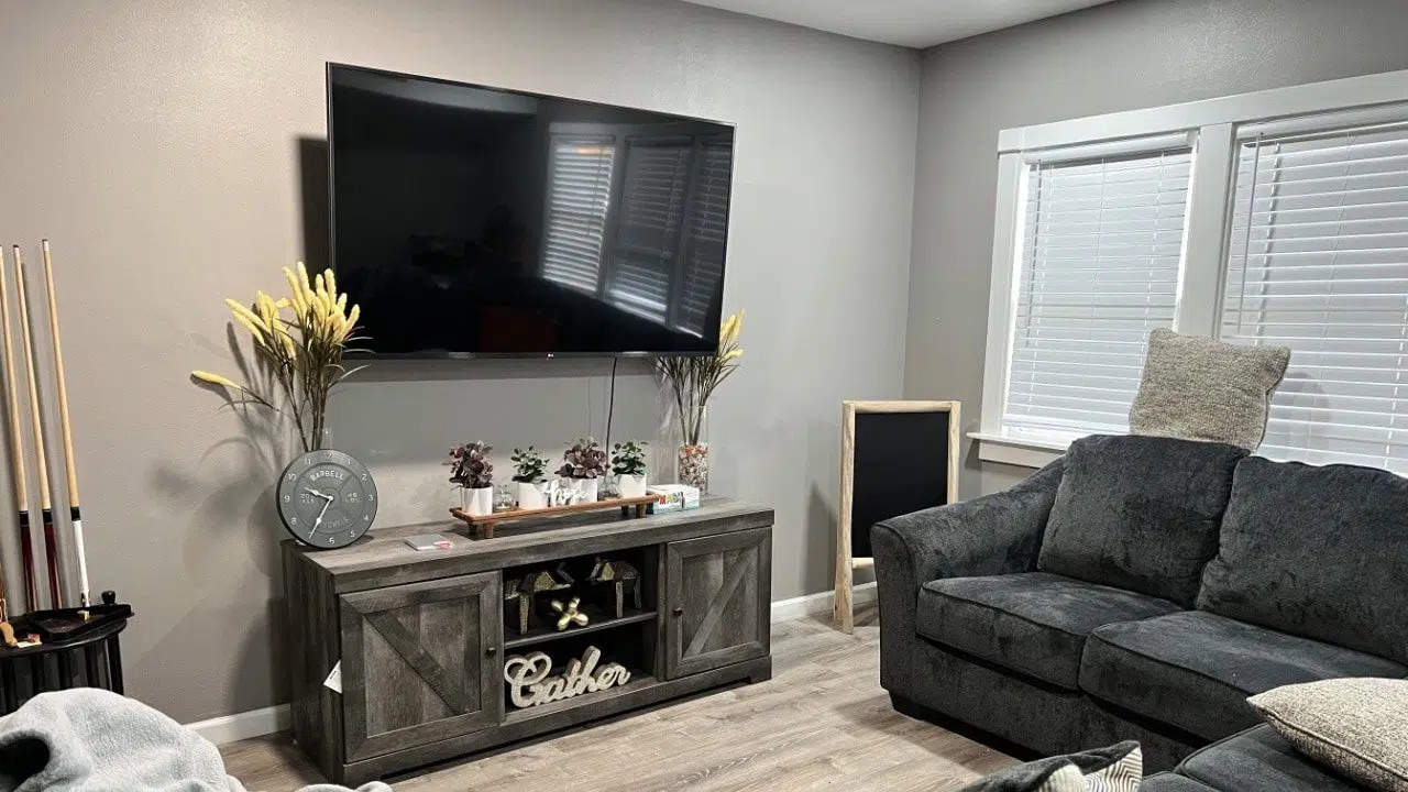 Flat-screen TV with couches and pool cues in corner