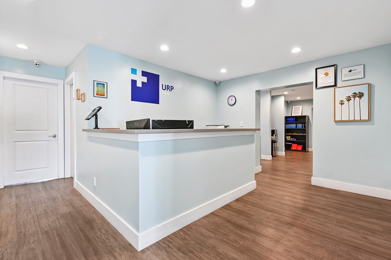 Reception desk with URP sign, light blue walls, and wood flooring.