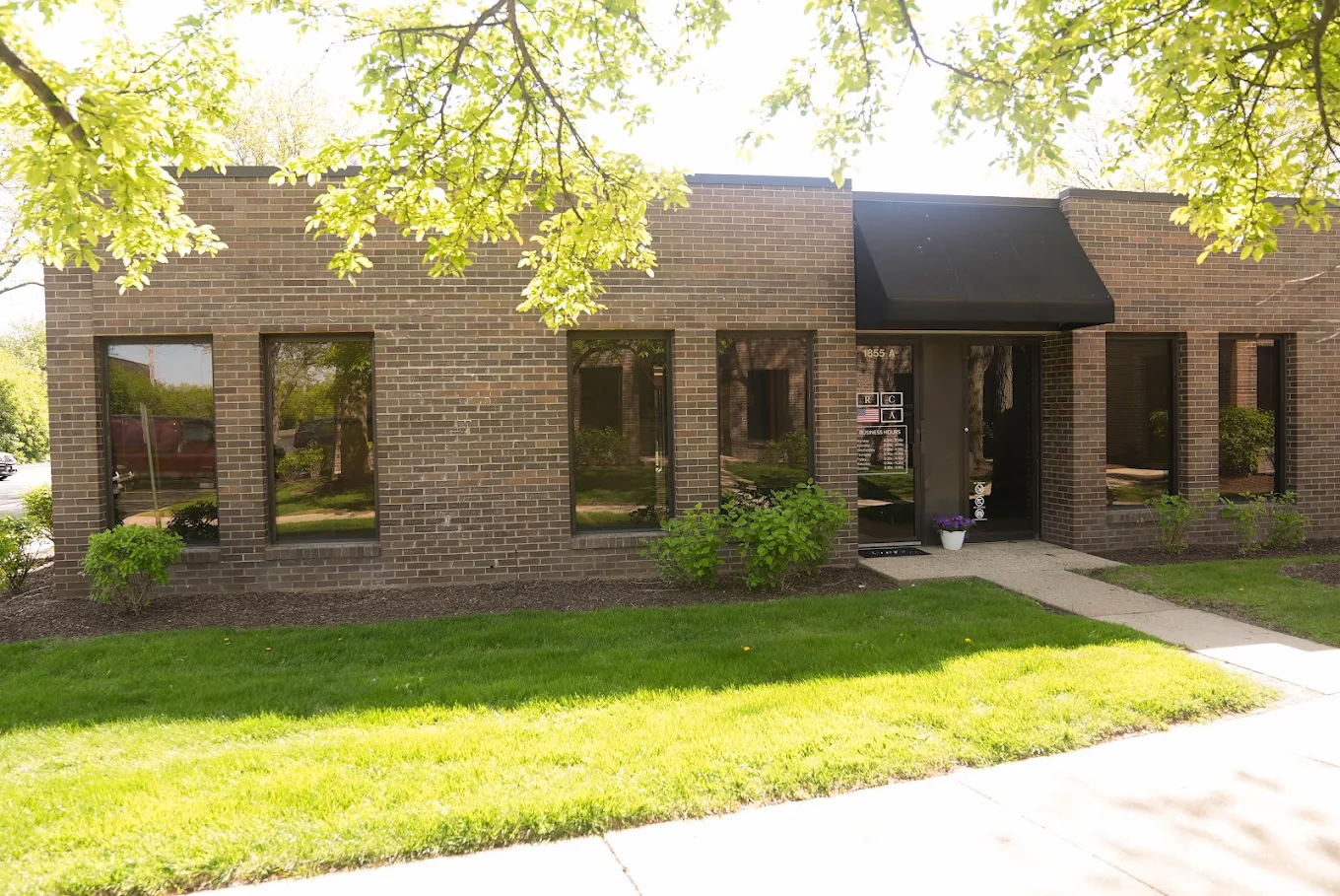 Brick outpatient center with lawn and shaded front walkway