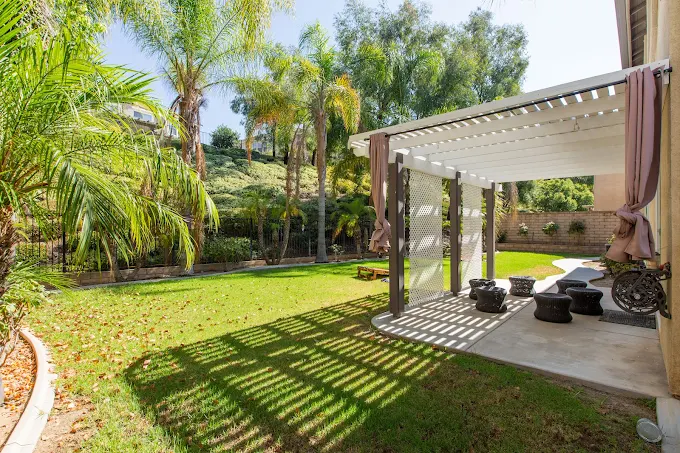 Shaded patio with seating surrounded by palm trees and lawn