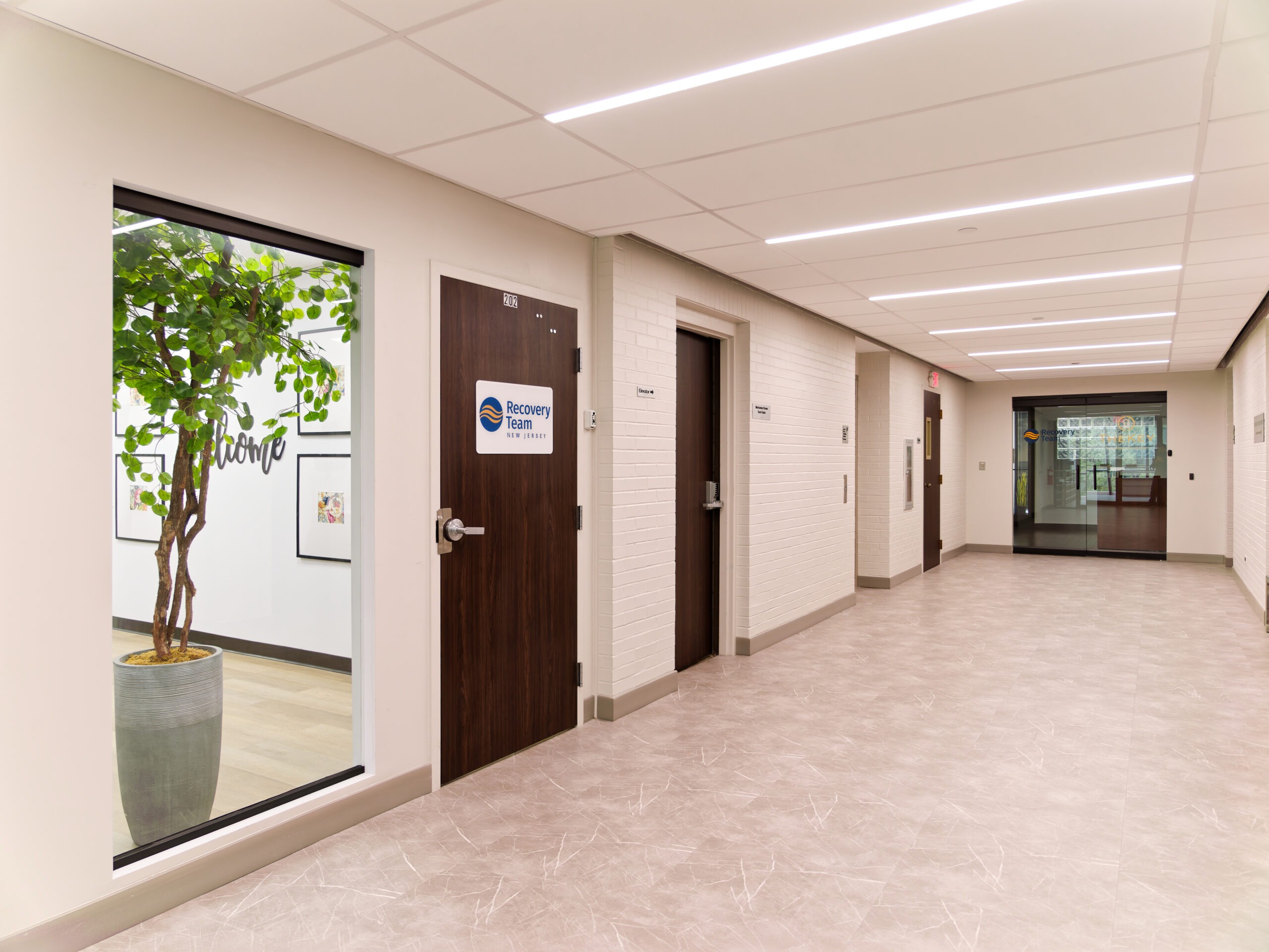 Bright clinic hallway with office doors and large interior window.