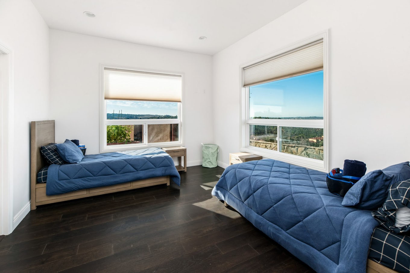 Shared bedroom with two beds and large windows.