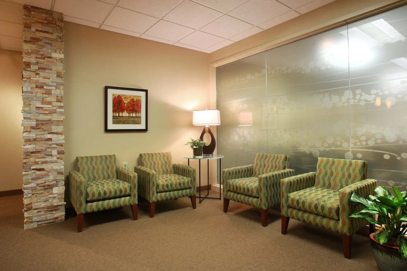 Lobby seating area with four armchairs, lamps, and plants