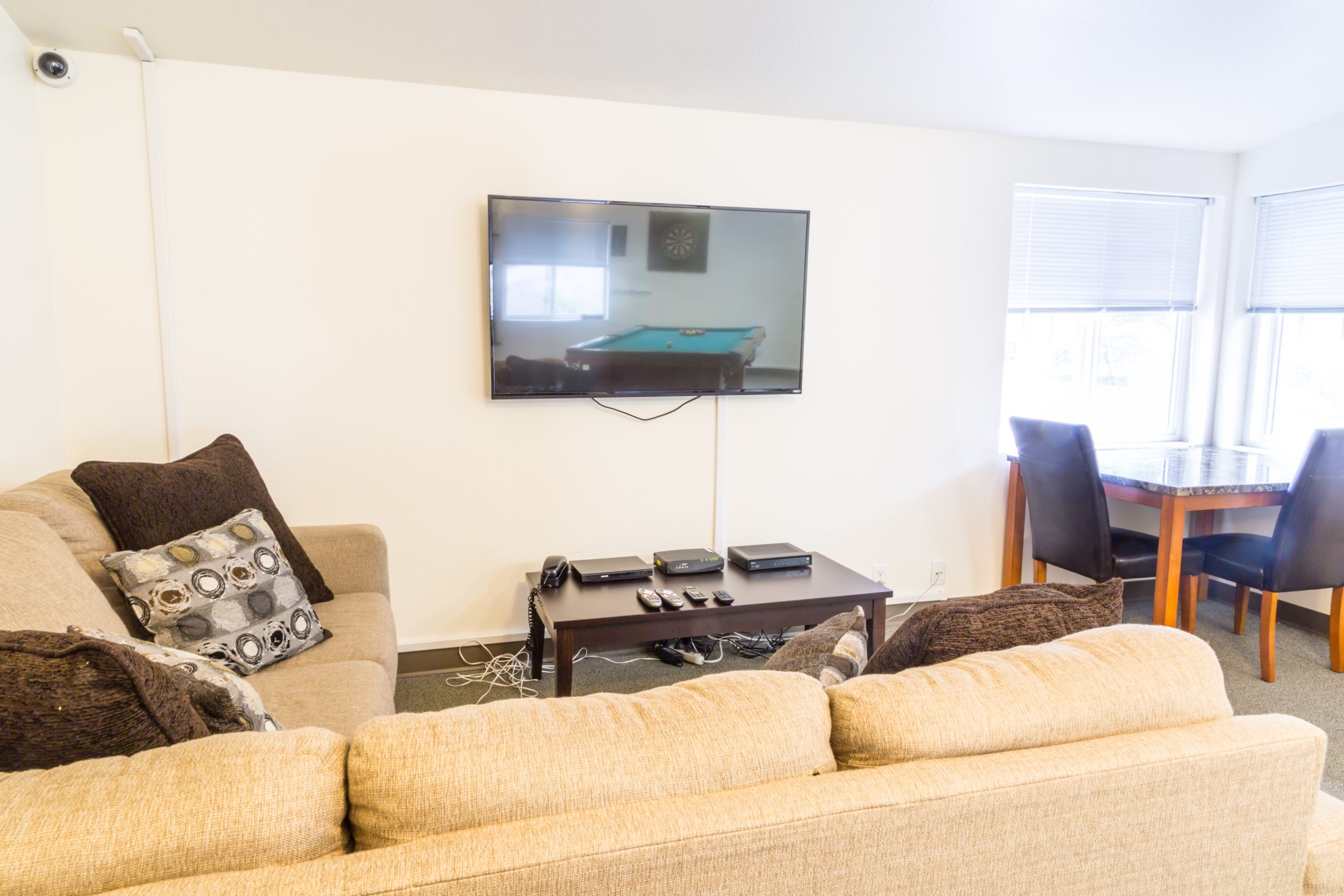 A living room with a sectional sofa, wall-mounted TV, and game table.