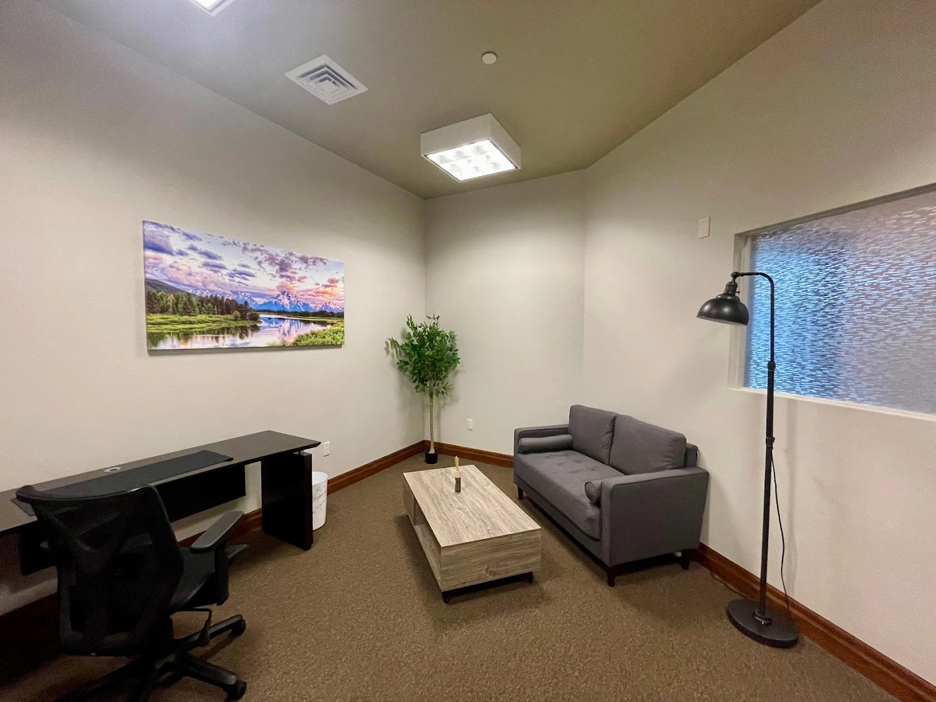 Small therapy office with desk, sofa, and wall art