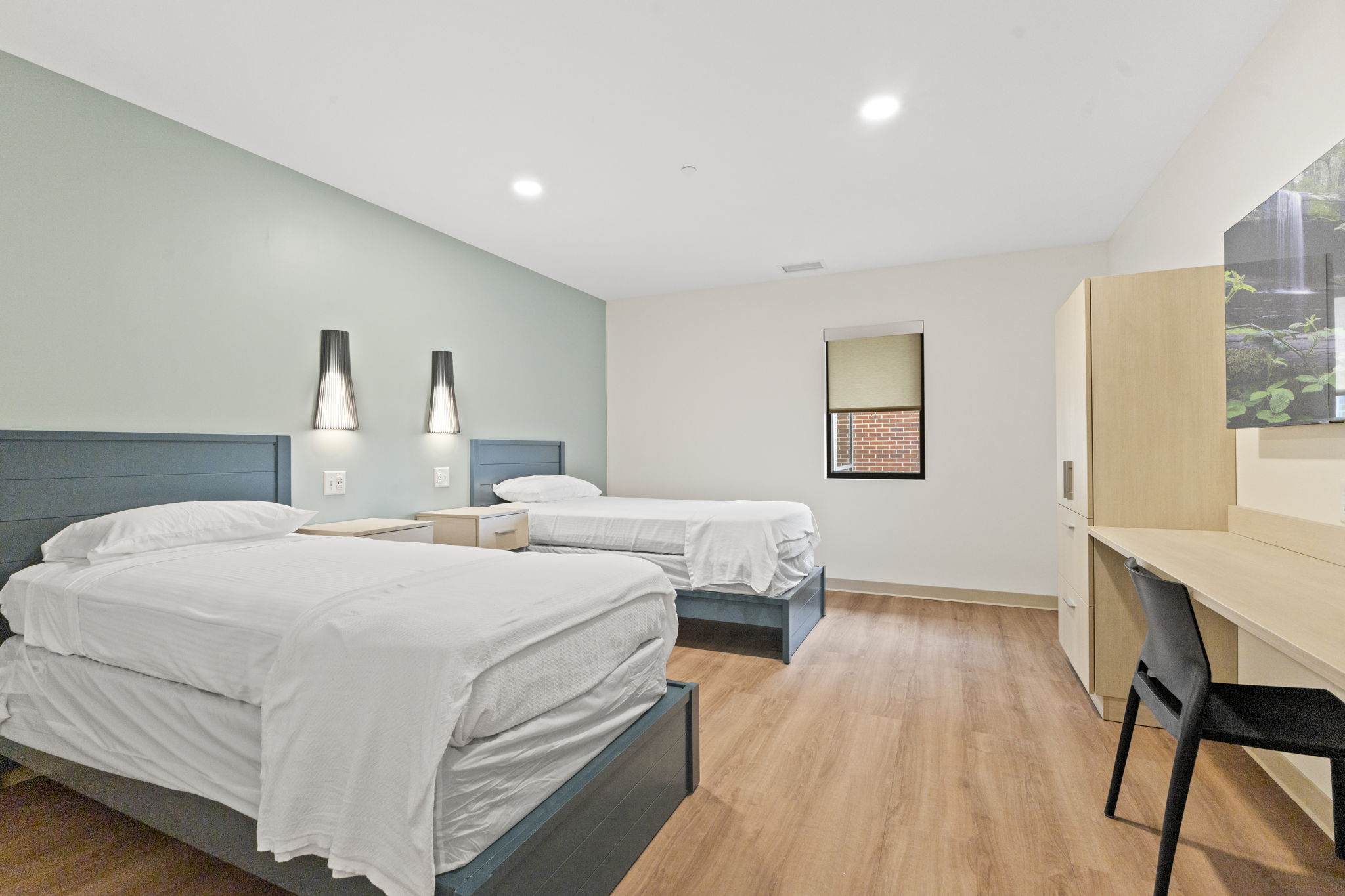 A bedroom with two beds, nightstands, and a window.