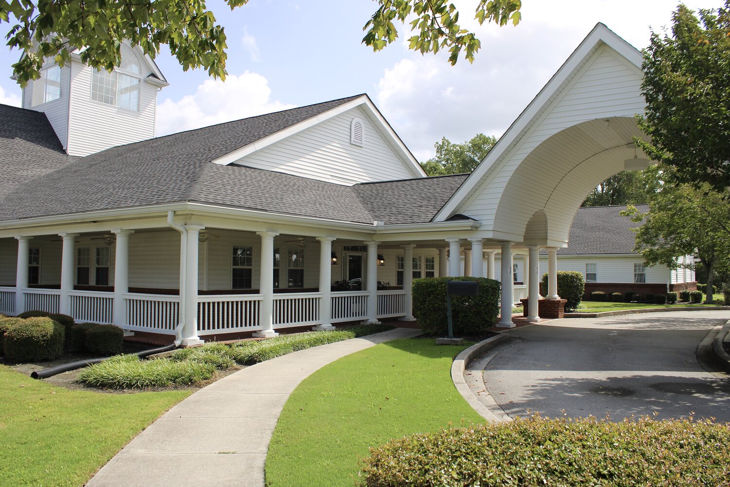 White-pillared building with circular driveway and lawn