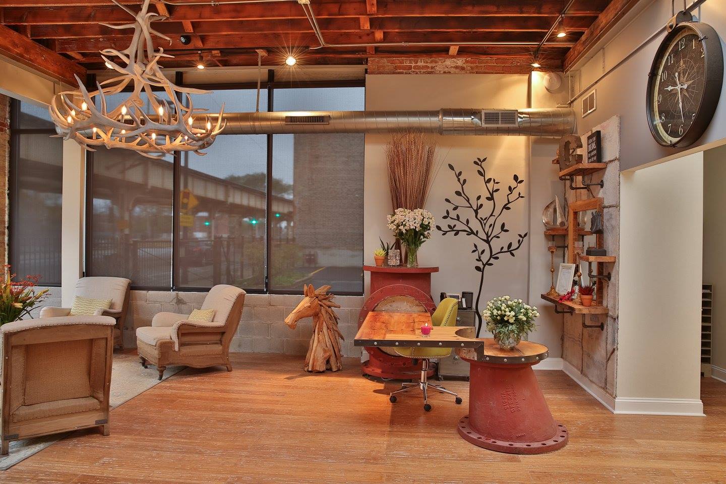 Warm lounge with armchairs, antler chandelier, and large windows