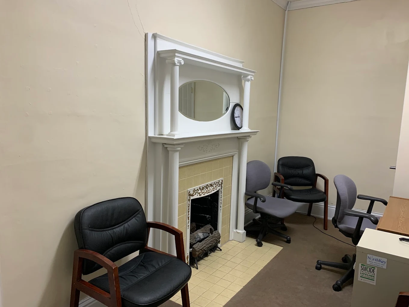Consultation room with chairs, desk, mirror, and fireplace