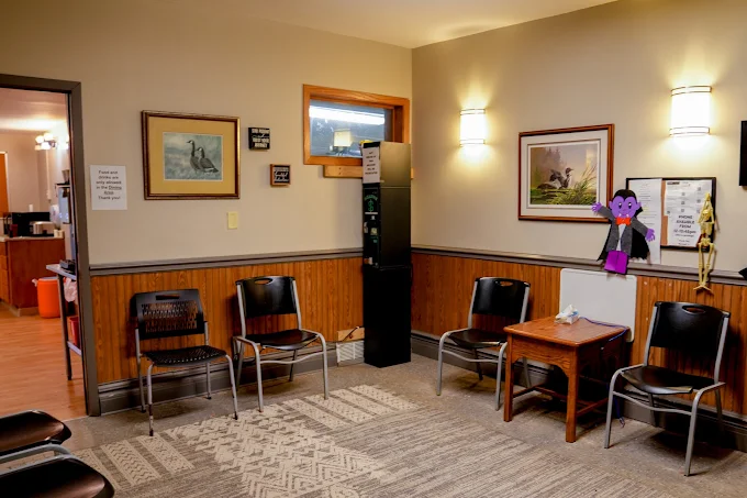 Waiting area with chairs, small tables, and wall art