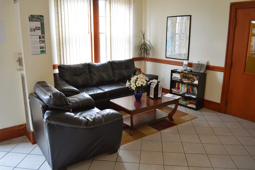 Lobby with black leather couches, a coffee table, bookshelf, and flowers