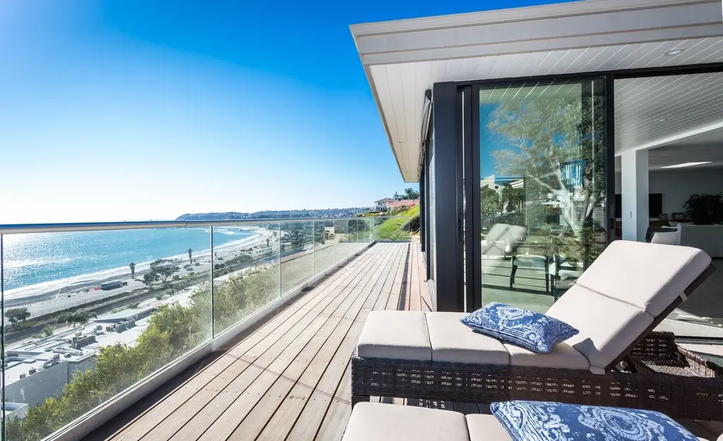 Ocean-view balcony with lounge chairs and glass railing.