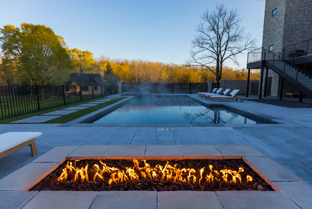 Outdoor fire pit beside a heated pool in a scenic setting
