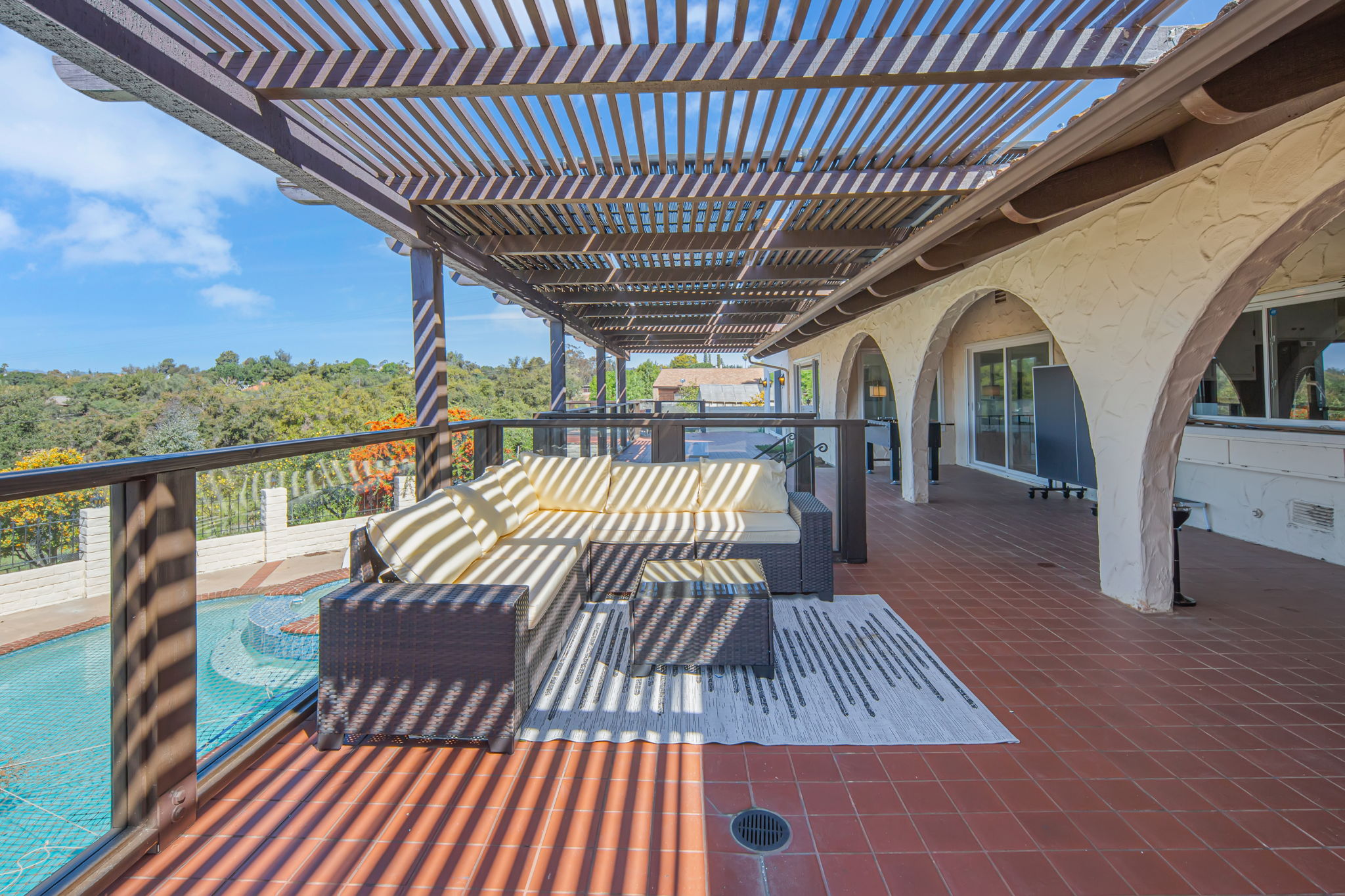 Covered patio with seating overlooking the pool