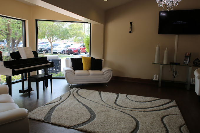 Lounge area with white couches, large windows and a piano.