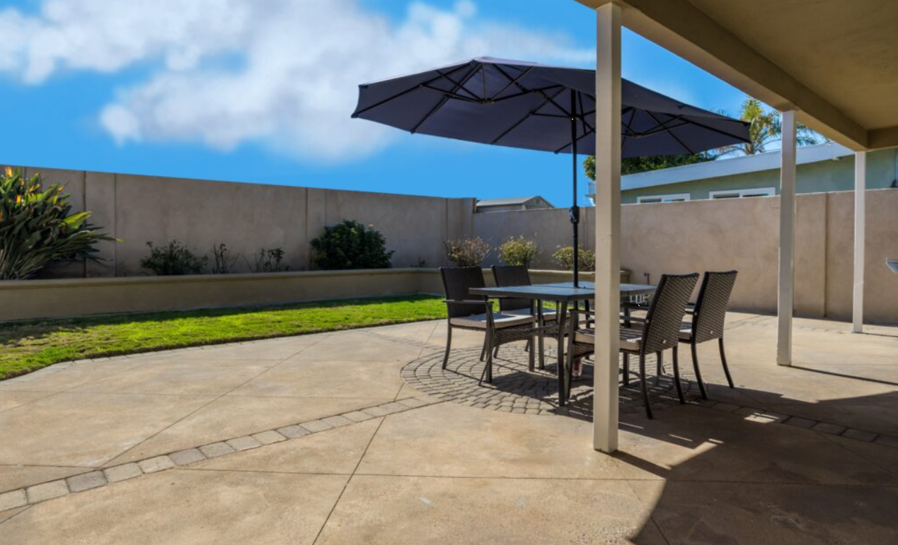 Patio with table, chairs, and umbrella in fenced backyard