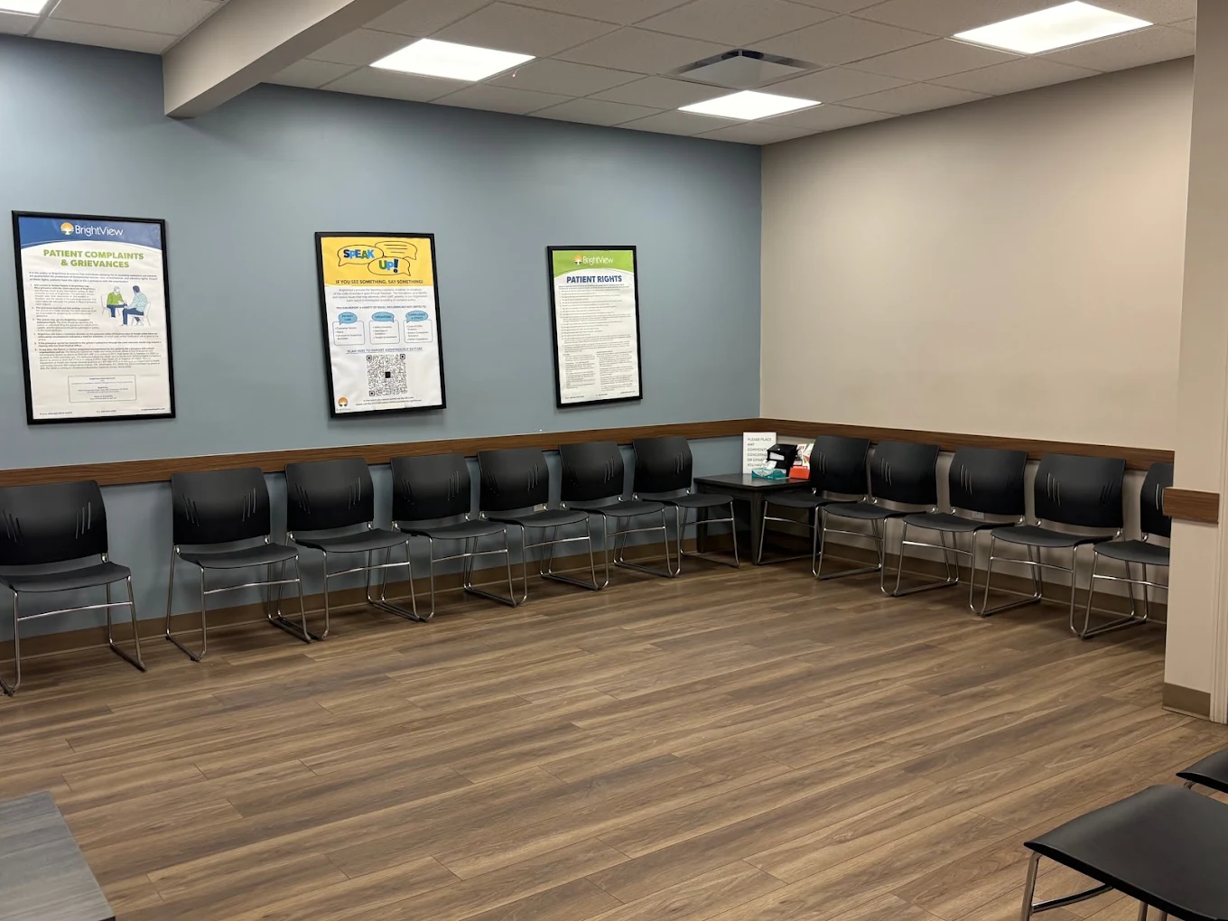 Waiting area with rows of black chairs and patient information posters
