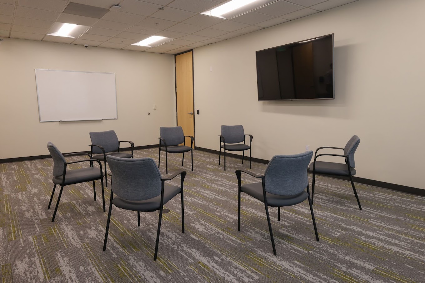 Therapy room with chairs arranged in a circle and a whiteboard.