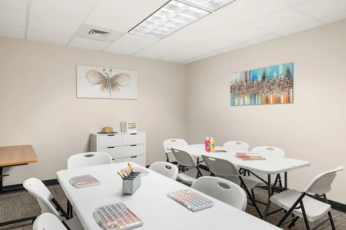 Art therapy classroom with tables, chairs, and creative supplies