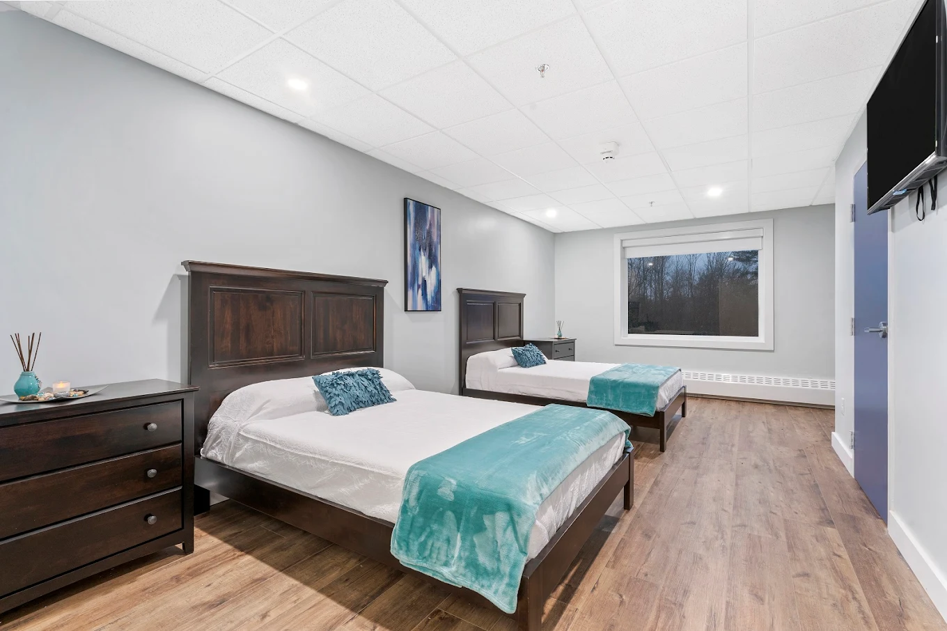 Room with two beds, dark wood furniture, and soft teal accents