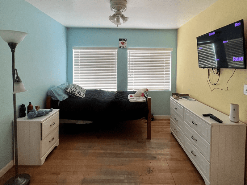 Bedroom with twin bed, TV, and two white dressers
