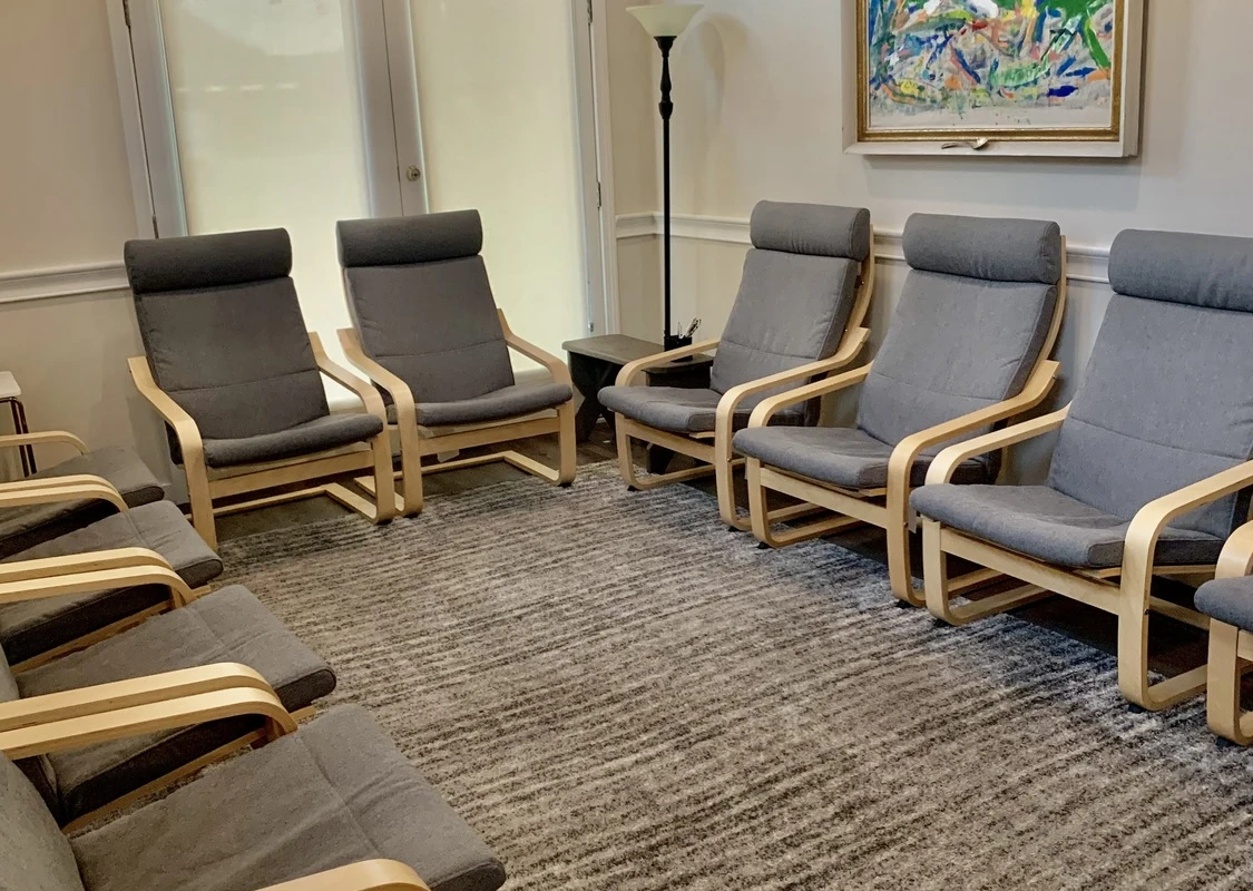 Circle of wooden chairs with gray cushions on carpeted floor