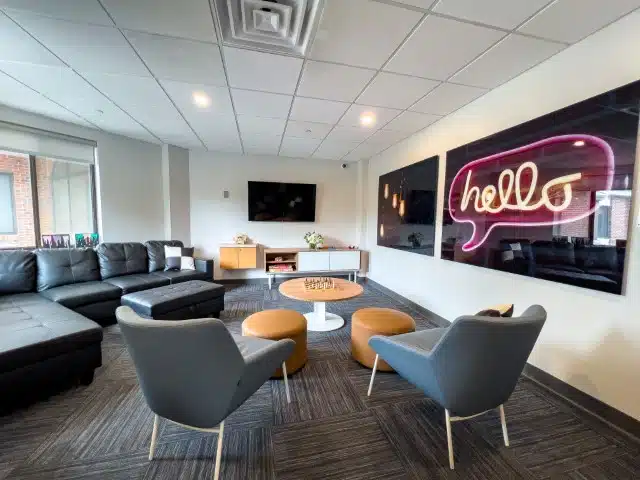 A cozy lounge with modern furniture and a neon "hello" sign.