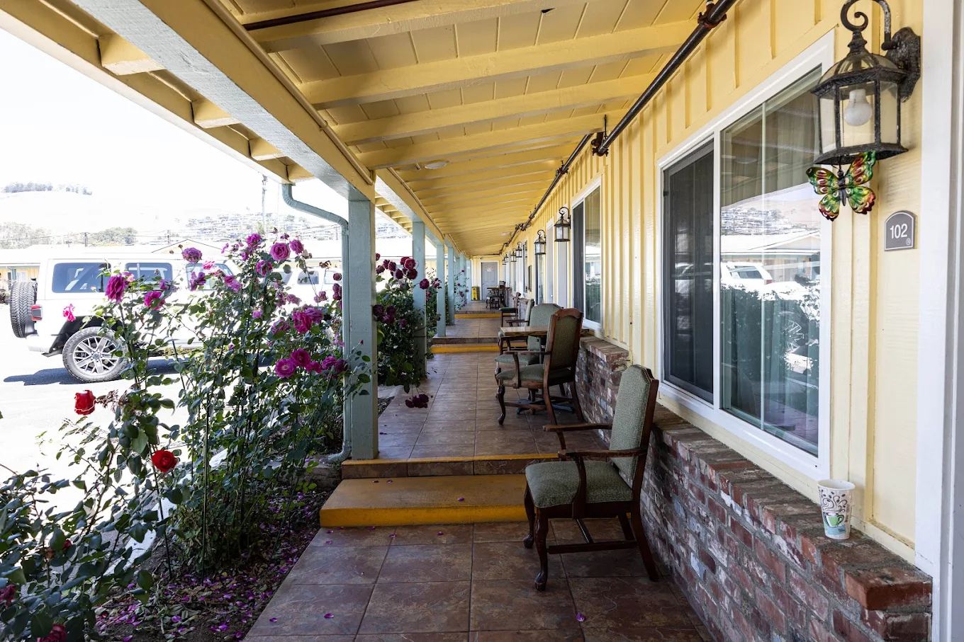 Covered patio with wooden benches, tables, and flowering plants