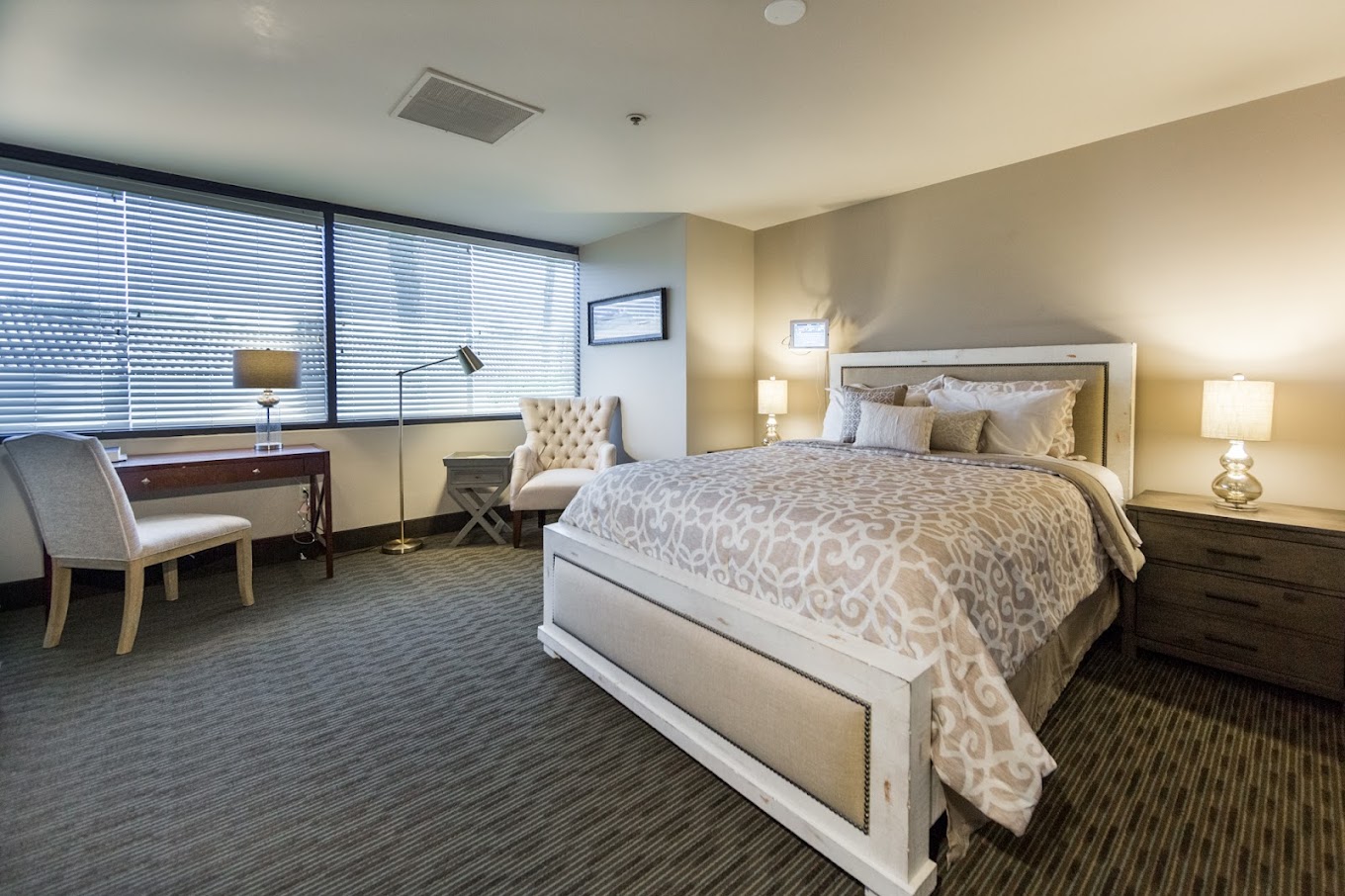 A bedroom with a large bed, desk, and cozy seating area