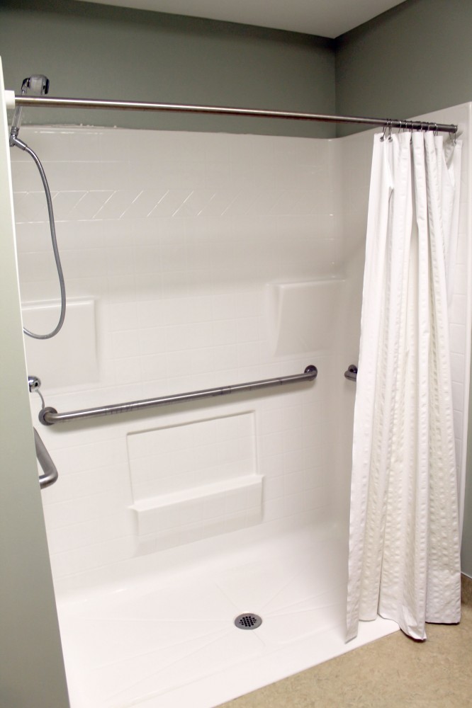 Accessible walk-in shower with grab bars and white curtain.