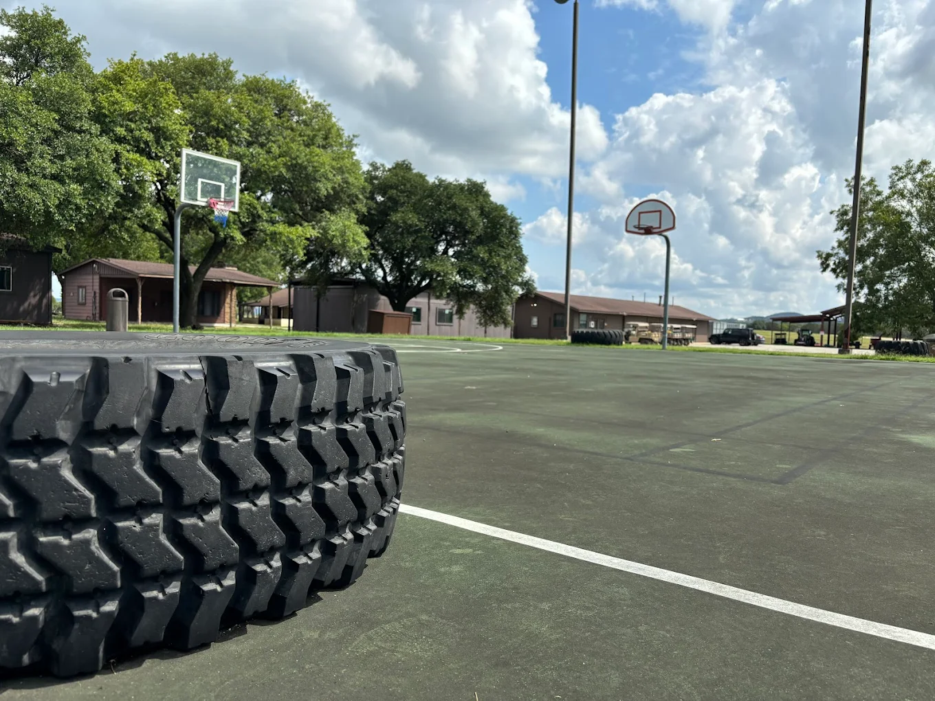 Basketball court with hoop and tractor tire on sunny day