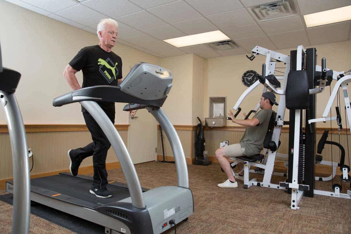 Two men using gym equipment in exercise room