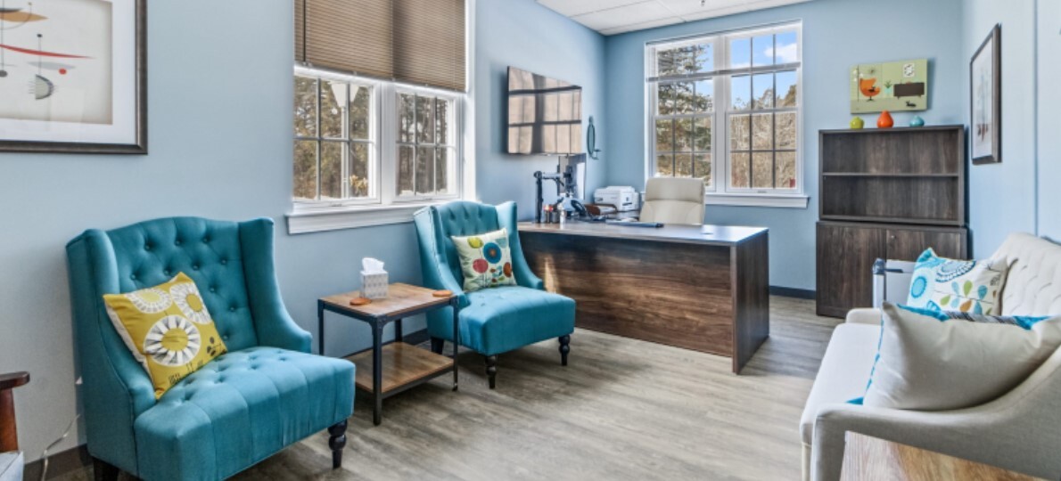 Therapy room with chairs, a desk, and windows.