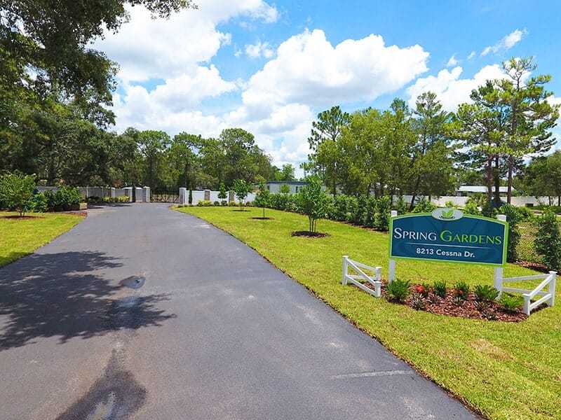Driveway entrance with sign and landscaped trees