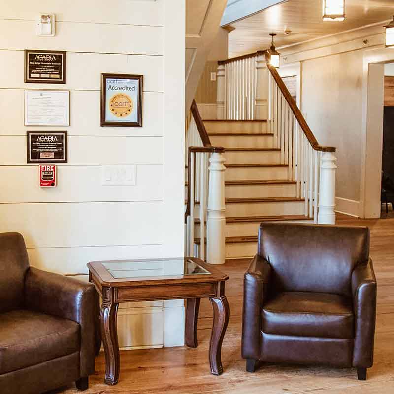 Interior lobby with staircase, seating, and framed accreditations on wall