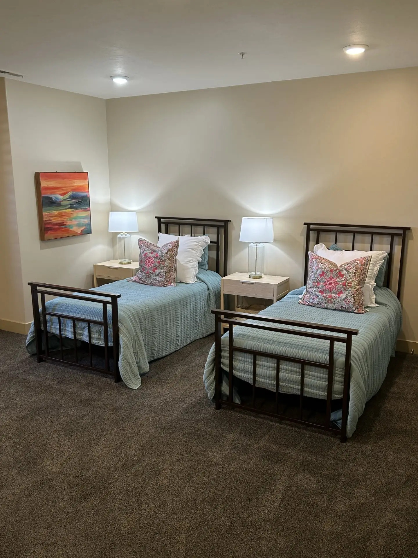 Two twin beds with teal bedding and floral pillows