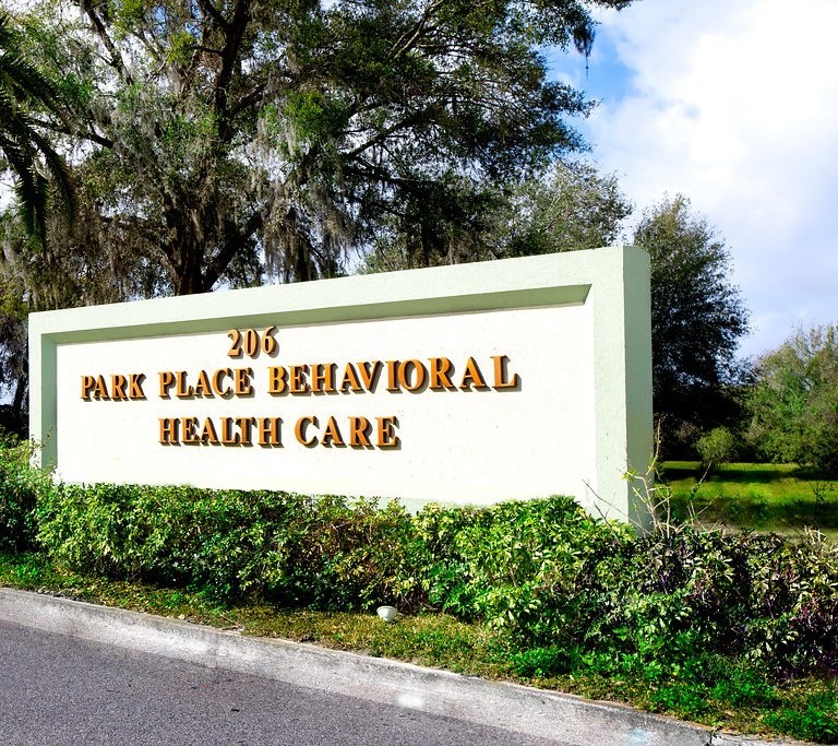 Facility sign with trees and address along the roadside