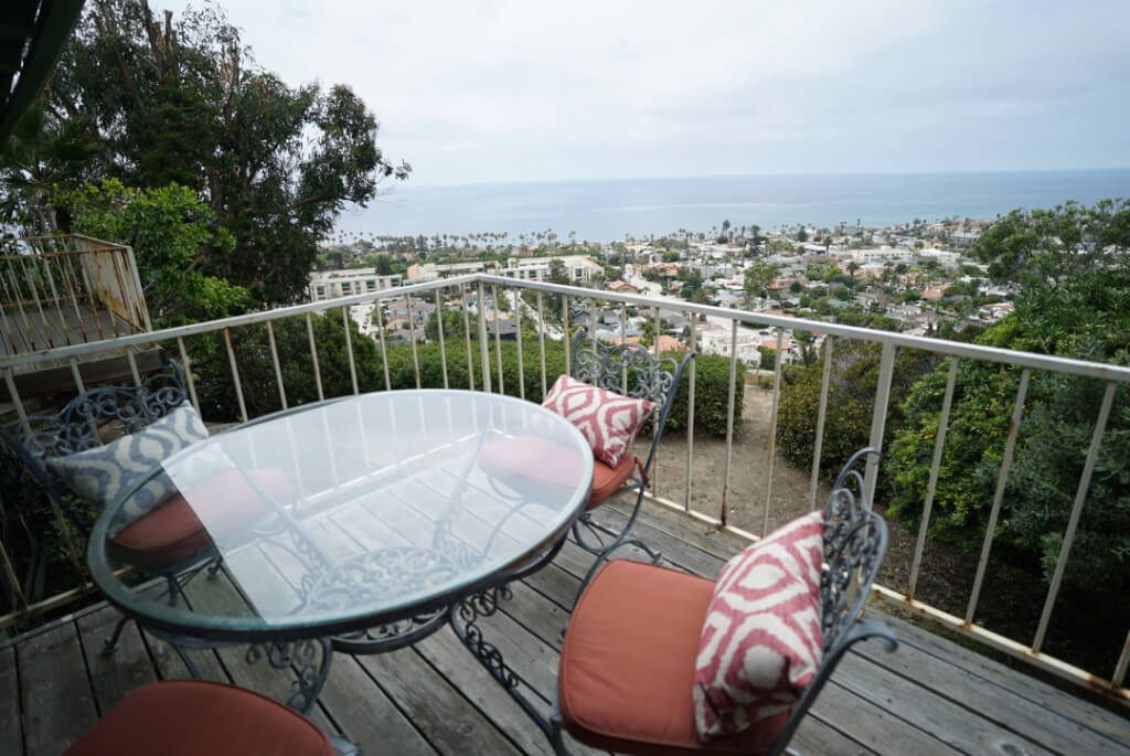 Patio table with red cushions overlooking ocean and city