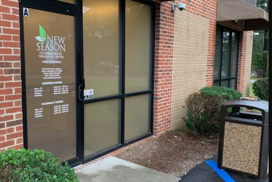 Entrance of New Season Treatment Center with a glass door and brick walls.