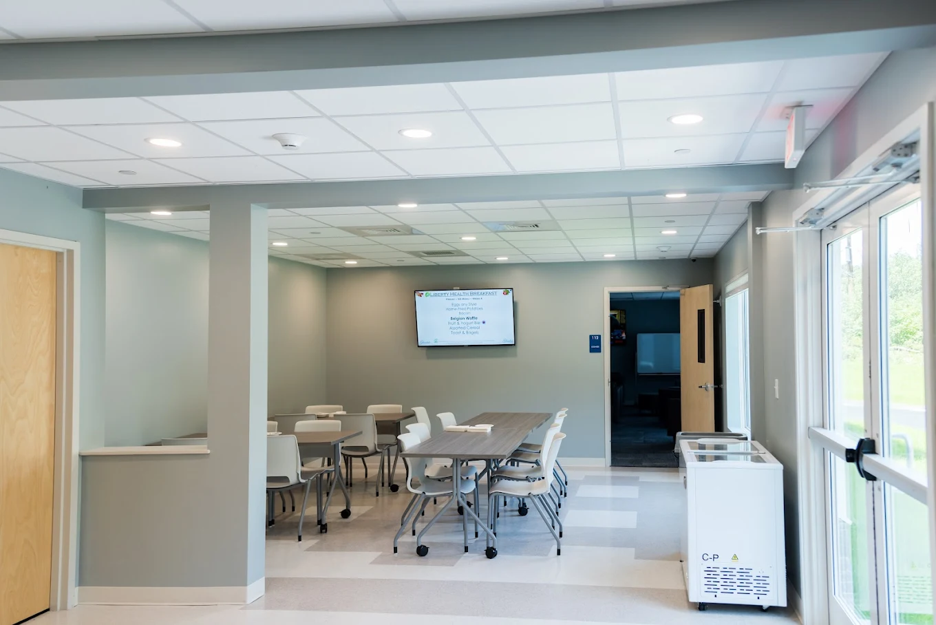 Meeting space with tables, chairs, and presentation screen