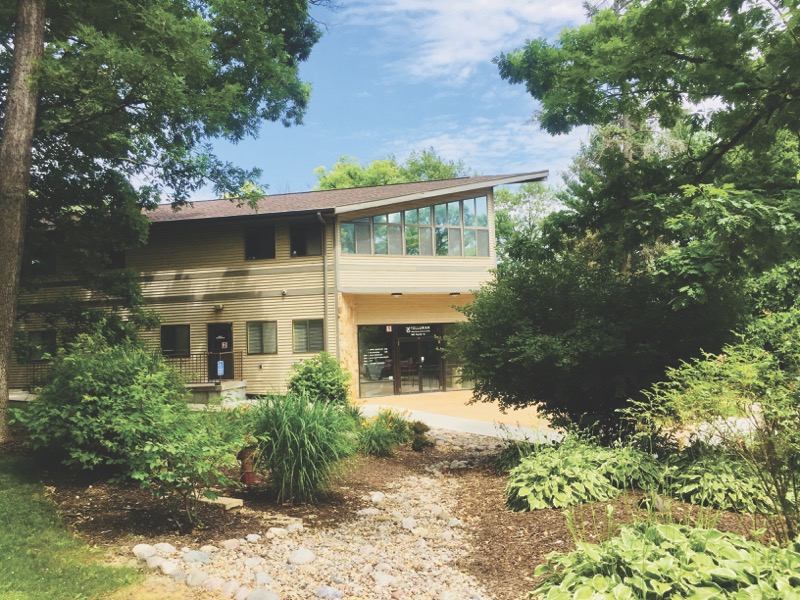 Two-story building surrounded by trees and garden path
