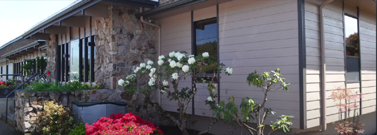 Stone and wood rehab center with blooming flowers and shrubs