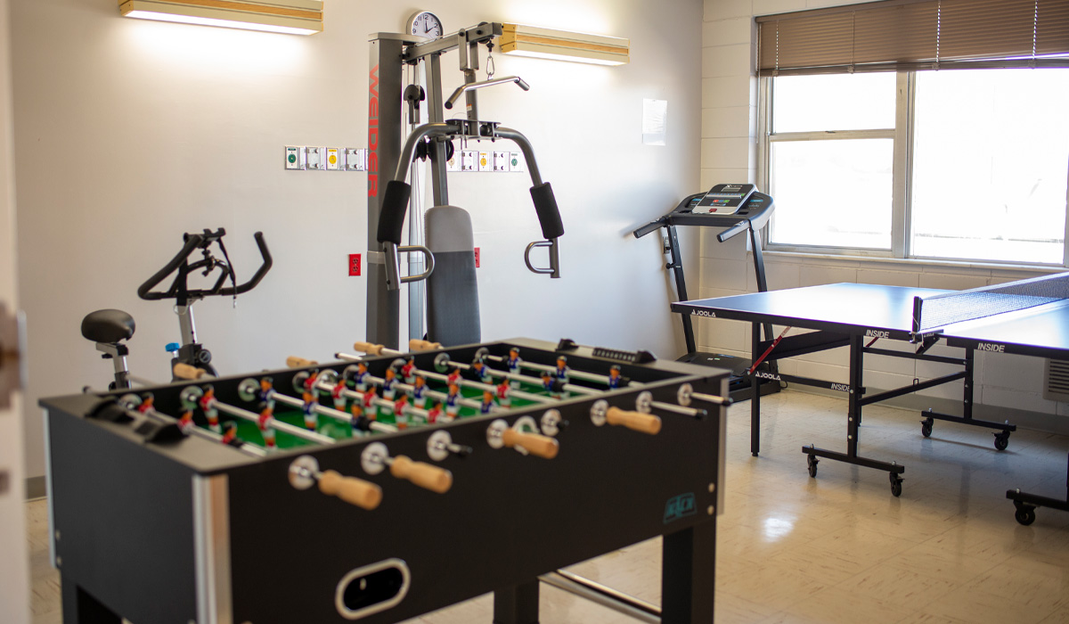 Gym room with exercise machines, foosball, and ping-pong table.