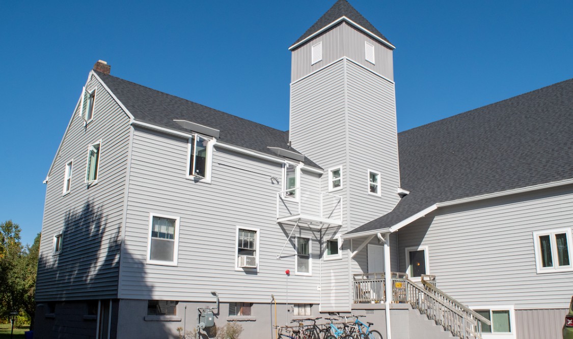 Gray rehab facility building with tower and outdoor stairs under blue sky
