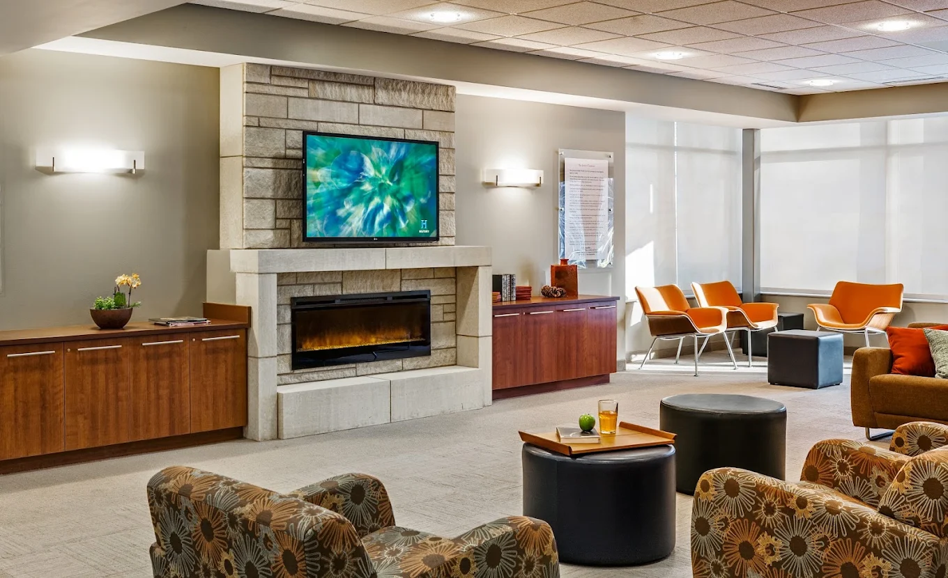 Comfortable lounge with fireplace, television, seating, and large windows